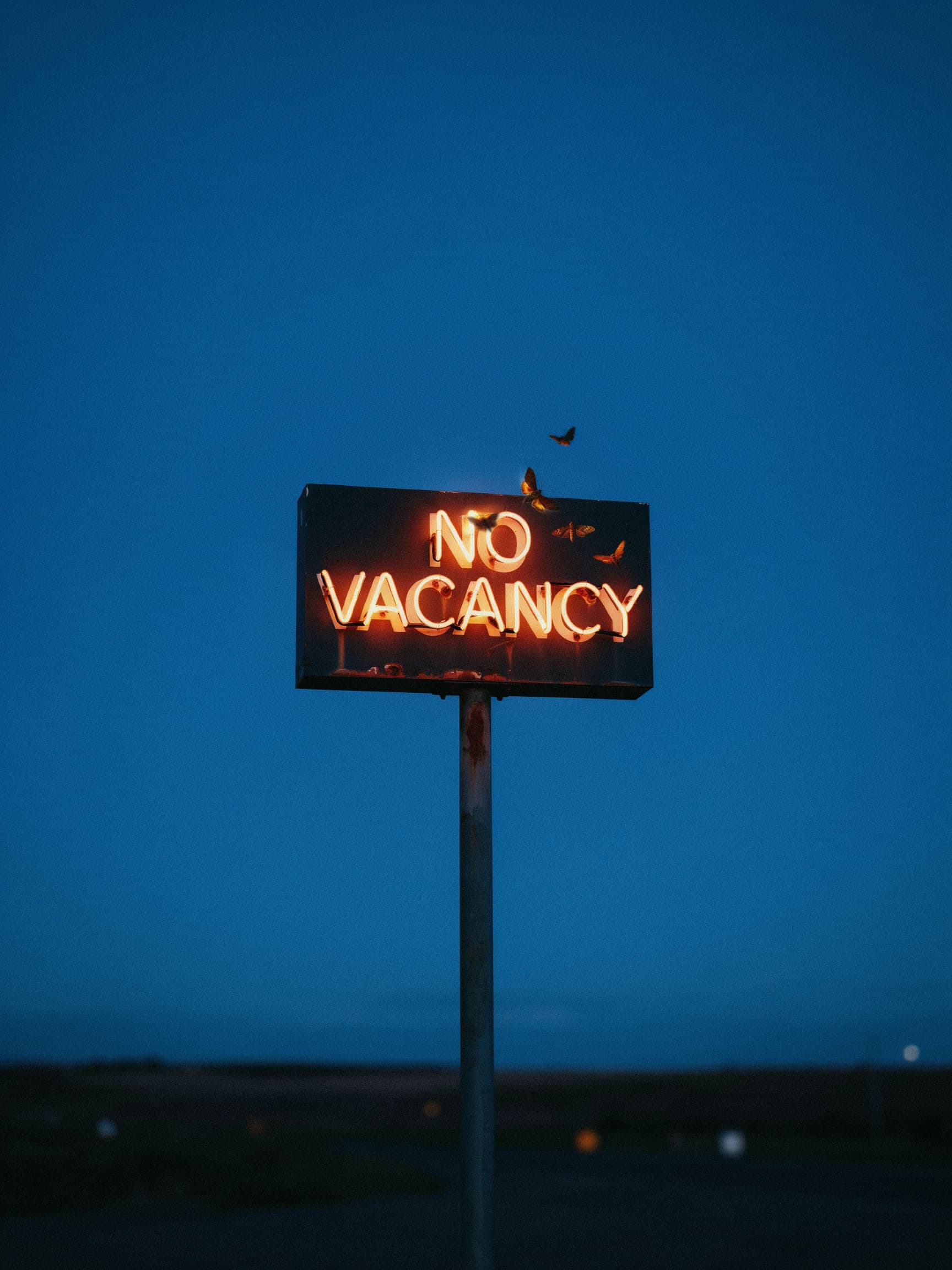 Vertical photograph of a two word roadside motel sign lit amber against a deep blue dusk sky, generated with Ideogram 4.0