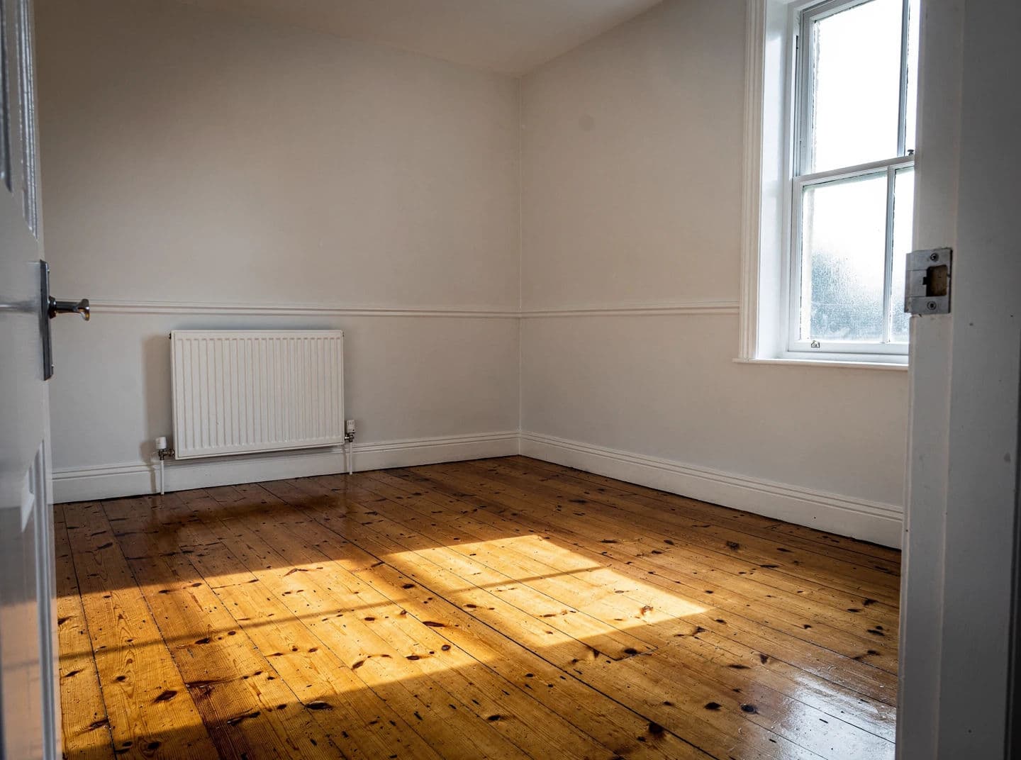 Listing photograph of a completely empty room with bare boards and no furniture, generated with Flux 2 Pro